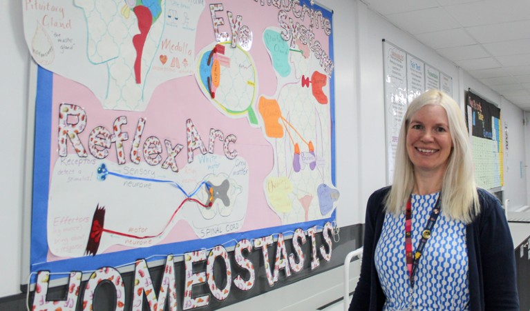 Charlotte Wood stands next to a scientific board in a classroom