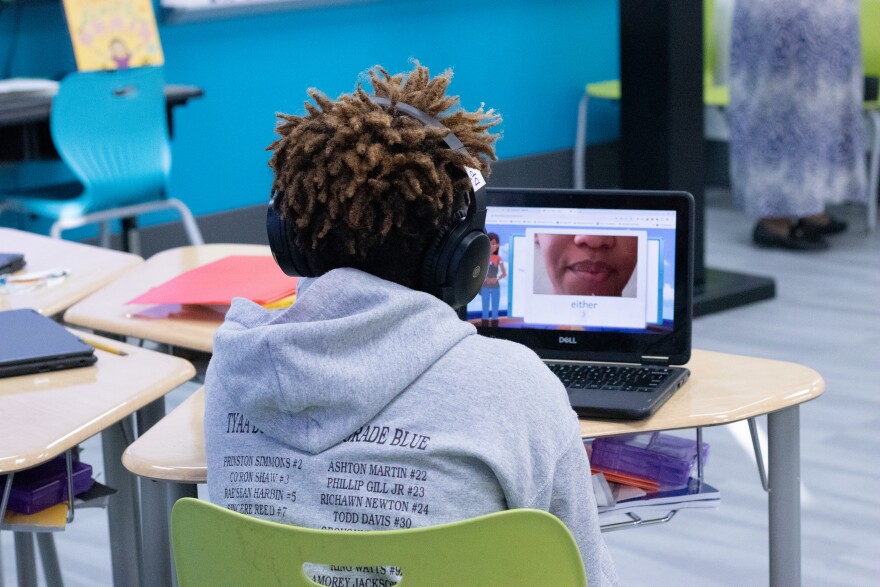 A fourth grader in Donye Filhiol's class at John Burroughs Elementary watches a video close-up modeling the word "either" on the Amira AI reading tutoring platform.