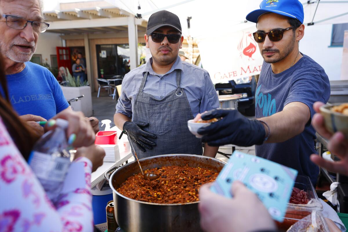 People serve chili at an outdoor festival 