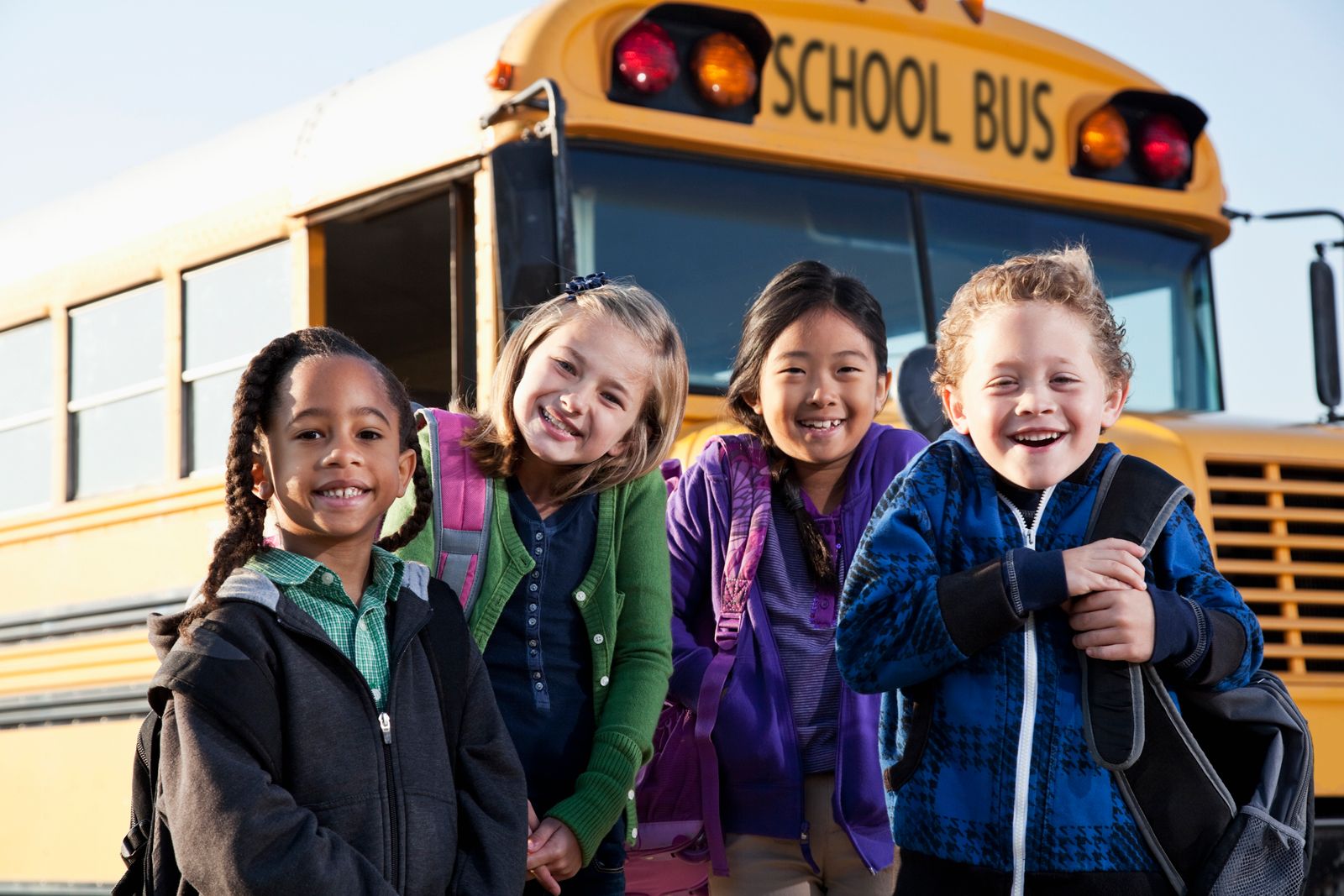 four-kids-standing-in-front-of-school-bus.jpg